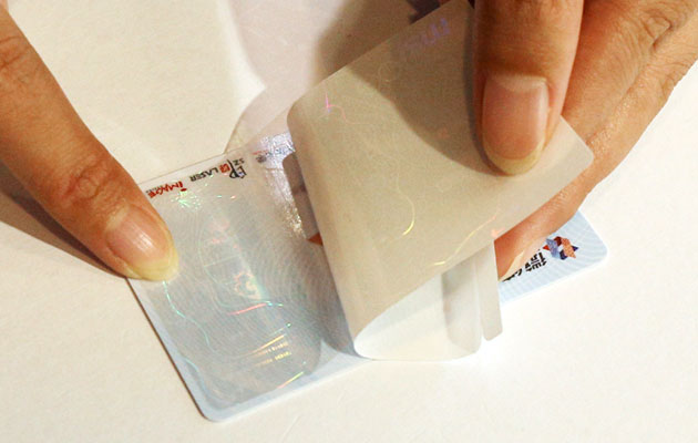 Manually apply optical cold lamination overlay to card surface
